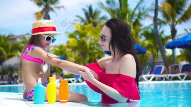 年轻的妈妈。应用太阳奶油孩子鼻子游泳池概念保护紫外线辐射
