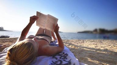 年轻的女性阅读<strong>书海</strong>滩波背景宽拍摄