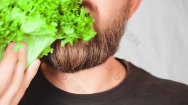 关闭脸英俊的男人。吃叶蔬菜