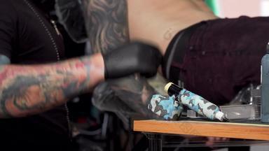纹身艺术家采取纹身机工作工作室