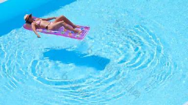 年轻的女人比基尼空气床垫大游泳池