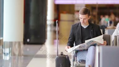 特写镜头智能手机男性手报纸内部机场休闲年轻的商人穿西装夹克年轻的男人。手机机场等待登机