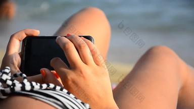 年轻的女孩智能手机海滩手指触碰刷屏幕现代智能手机