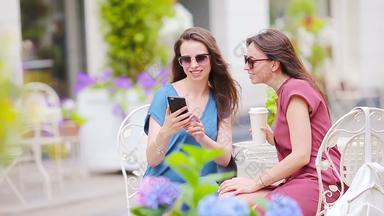 年轻的女孩采取自拍聪明的电话在户外咖啡馆女性购物袋坐着露天咖啡馆咖啡智能手机
