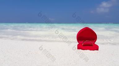 <strong>白色黄金</strong>建议环红色的天鹅绒心形状环盒子沙子清晰的水波崩溃海岸背景夏威夷
