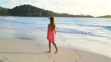 可爱的快乐女孩走白色海滩日落慢运动视频
