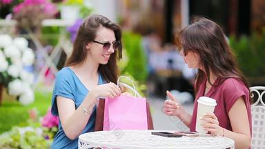 年轻的女孩在户外咖啡馆女性购物袋坐着露天咖啡馆咖啡智能手机