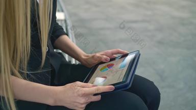 女人平板电脑板凳上正式的业务女人坐着板凳上办公室天井浏览平板电脑休闲