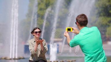 的男朋友采取图片朋友坐着背景喷泉年轻的男人。使照片女人街笑有趣的夏天