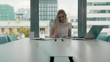年轻的业务女人会议房间论文优雅的金发碧眼的女人坐着长表格现代大厅办公室移动PC写作论文工作