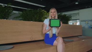 女人显示平板电脑办公室年轻的微笑金发碧眼的女人显示平板电脑绿色色度屏幕相机微笑办公室