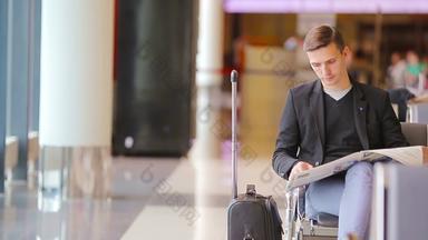 年轻的高加索人男人。报纸机场等待登机休闲年轻的商人穿西装夹克