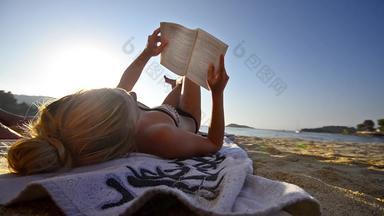年轻的女性阅读书海滩波背景