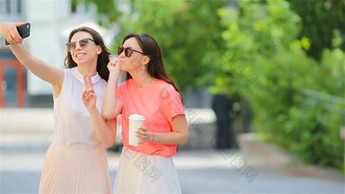 年轻的女孩采取自拍聪明的电话在户外女性购物咖啡智能手机