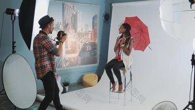 时尚的非洲模型摆姿势红色的伞酒吧高椅子<strong>时尚杂志</strong>照片拍摄
