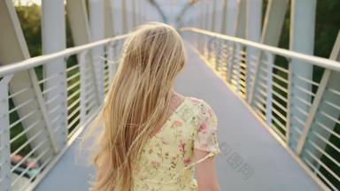 女人扔头发桥回来视图金发女郎女孩运行行人桥扔头发