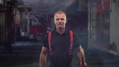 消防队员肖像穿衬衫裤子持有斧烟火卡车背景
