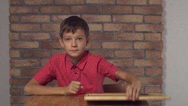 孩子坐着桌子上持有<strong>白板</strong>纸上的内容刻字背景红色的砖墙