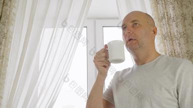 成人男人。喝早....咖啡舒适的厨房窗口背景肖像快乐的男人。享受热<strong>茶杯首页</strong>厨房