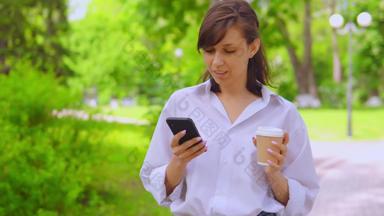 年轻的女商人聊天在线喝咖啡漫步公园