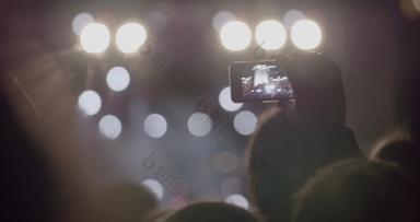 观众男人。记录视频阶段前面明亮的聚光灯智能<strong>手机</strong>户外音乐音乐会