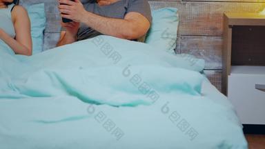 快乐的年轻的夫妇智能手机穿睡衣床上晚上睡眠