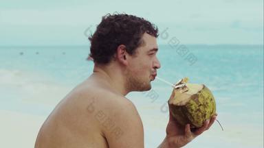 男人。海滩喝椰子