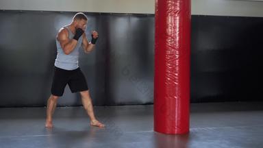 拳击手培训健身房冲袋男人。自由搏击选手拳击锻炼室内有氧运动锻炼准备战斗