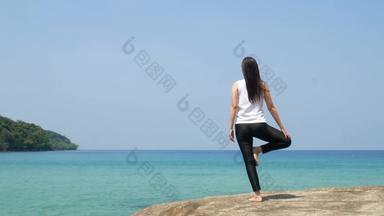 女人站腿练习瑜伽木桥海夏天假期有吸引力的年轻的亚洲女人站瑜伽构成