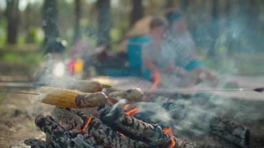关闭香肠玉米串煮熟的火烟夏天家庭野营假期帐篷森林慢运动替身拍摄