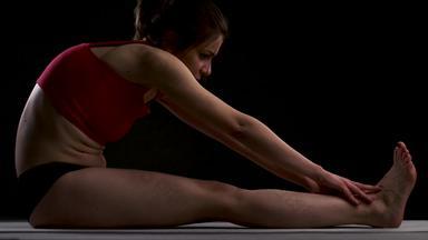 女孩练习瑜伽伸展运动武器腿手触碰脚