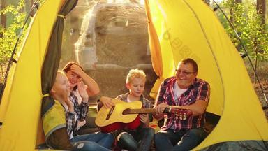 快乐旅游家庭有趣的内部野营帐篷阳光明媚的森林友好的家庭笑唱歌首歌吉他旅游帐篷营地家庭森林徒步旅行假期