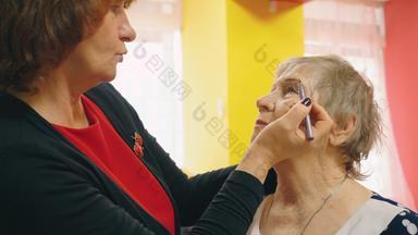 上了年纪的女人使化妆朋友应用眼线笔眉使形式