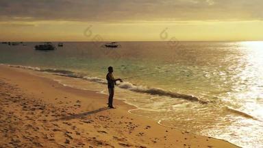 垂钓者好少年假期享受活动海滩清洁白色沙子蓝色的背景