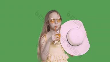 年轻的女孩太阳镜喝橙色汁玻璃稻草透明的绿色背景少年女孩穿他喝水果鸡尾酒α通道键控绿色屏幕