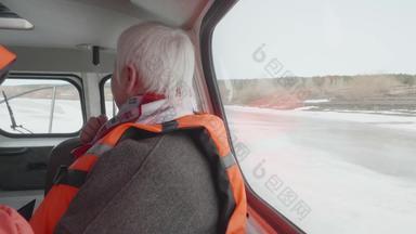 高级女人安全夹克骑气垫船冻河上了年纪的女人灰色头发乘客气垫船移动冬天河