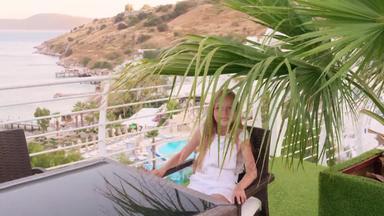 快乐女孩坐着棕榈树叶子户外阳台海视图微笑女孩夏天阳台度假胜地酒店海高地景观热带度假胜地酒店海海岸