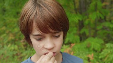 肖像思考少年男孩夏天公园英俊的少年男孩咀嚼口香糖户外沉思的脸年轻的男孩绿色树背景