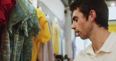 年轻的男性销售助理挂t恤衣服Rails古董衣服商店