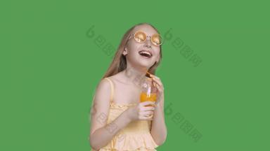 笑女孩持有手橙色汁玻璃透明的绿色背景快乐女孩少年黄色的眼镜橙色鸡尾酒绿色背景α通道键控绿色屏幕