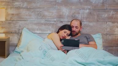 高加索人夫妇睡衣说谎床上平板电脑电脑