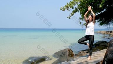 女人站腿练习瑜伽木桥海夏天假期有吸引力的年轻的亚洲女人站瑜伽构成