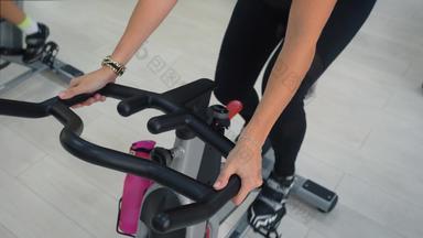 健身女人旋转静态自行车骑自行车类健身房肖像体育运动女人呼吸有氧运动培训室内自行车健身俱乐部集团自行车健身房