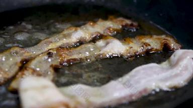 特写镜头脆皮培根片煎锅很多石油猪肉培根铁板吸烟热锅烹饪不健康的食物早餐