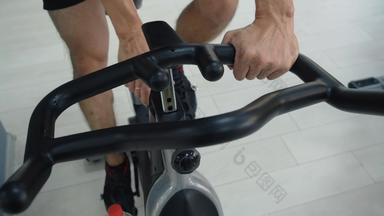 男性手持有处理静态自行车健身俱乐部运动员培训健身房自行车室内自行车健身房健身男人。设置自行车骑自行车类