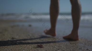 男人。走步进站金沙子海海滩超级慢运动低角拍摄男性腿走海洋光着脚桑迪海岸波夏天海岸线
