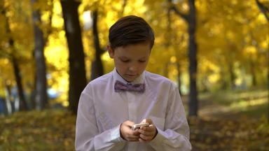 年轻的的家伙玩电话走秋天公园镜头替身拍摄