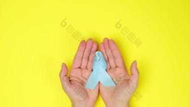 女手持有蓝色的丝绸丝带形状循环蓝色的背景象征战斗治疗前列腺癌癌症前viewfemale手持有蓝色的丝绸丝带形状循环