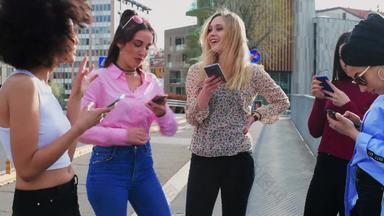 集团女孩年轻的女性女朋友站手机聊天发短信笑