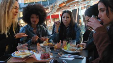 集团年轻的<strong>女性</strong>坐着表格在户外吃喝